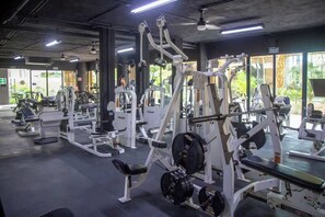 A gym with various weightlifting equipment, benches, and cardio machines.