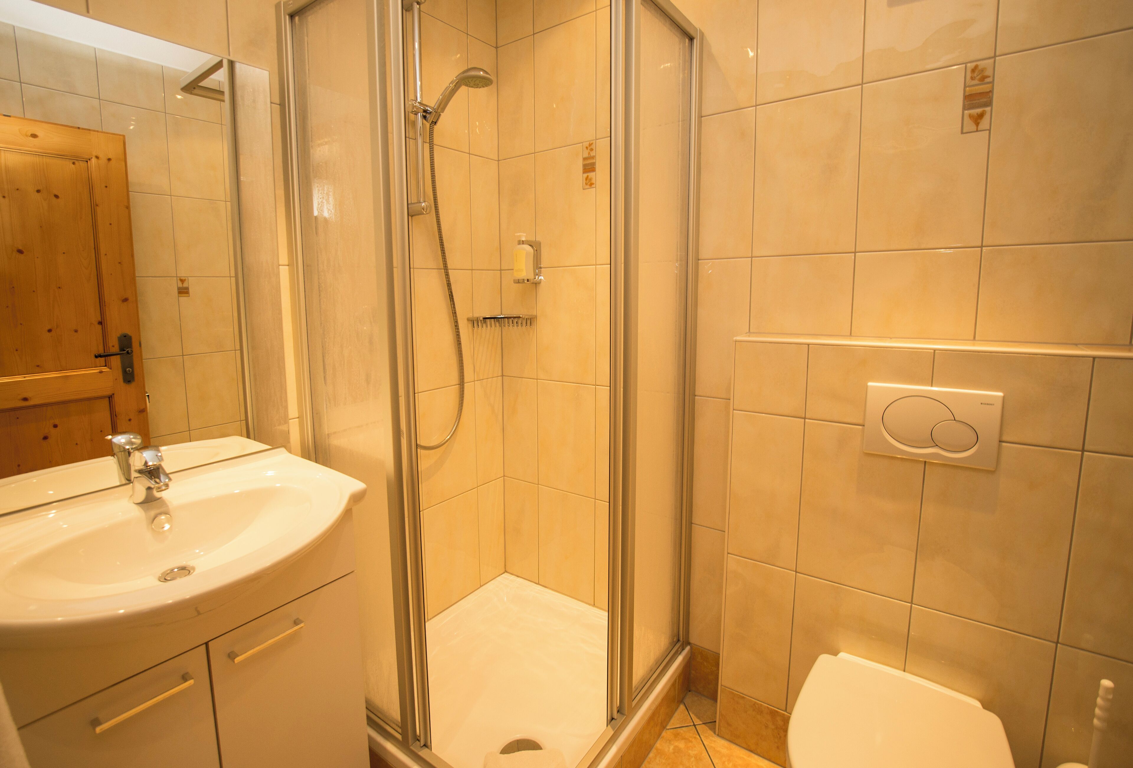 Un baño con ducha envuelta en vidrio, un lavabo e inodoro.