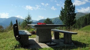 A stone picnic table with benches, set against a mountainous backdrop. - Flachauer Bergkristall (Flachau)