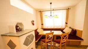 A cozy dining area with a wooden table, four chairs, and a bench with cushions. A small kitchen counter is visible to the left. - Flachauer Bergkristall (Flachau)
