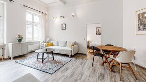 Una sala moderna con un sofá blanco, una mesa redonda de madera y una mesa de comedor con sillas.