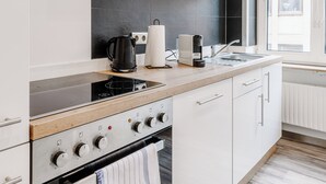 Una cocina moderna con armarios blancos, una estufa negra y una ventana que deja entrar luz natural.