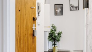 Un pasillo con una puerta de madera, una planta en maceta y cuadros en la pared.