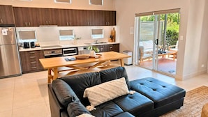 Eine moderne Küche mit dunklen Holzausführungen, einem Edelstahlkühlschrank und einem Holztisch.