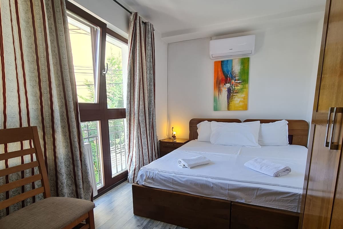 Ein Schlafzimmer mit einem hölzernen Bett, einem Sessel und einem Fenster mit Vorhängen.