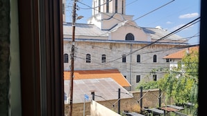 Vista di un edificio con una cupola e un campanile, vista attraverso una finestra con ringhiera in metallo.