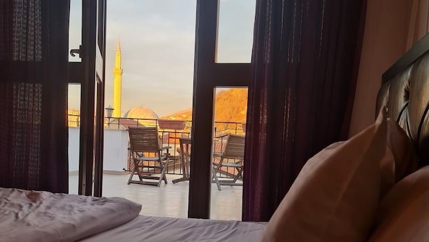 Camera d'albergo con un letto, vista su una moschea e area salotto esterna.