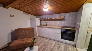 Una cucina compatta con soffitto in legno, forno integrato e una piccola zona pranzo con un divano marrone e un tavolo con una pianta in vaso.