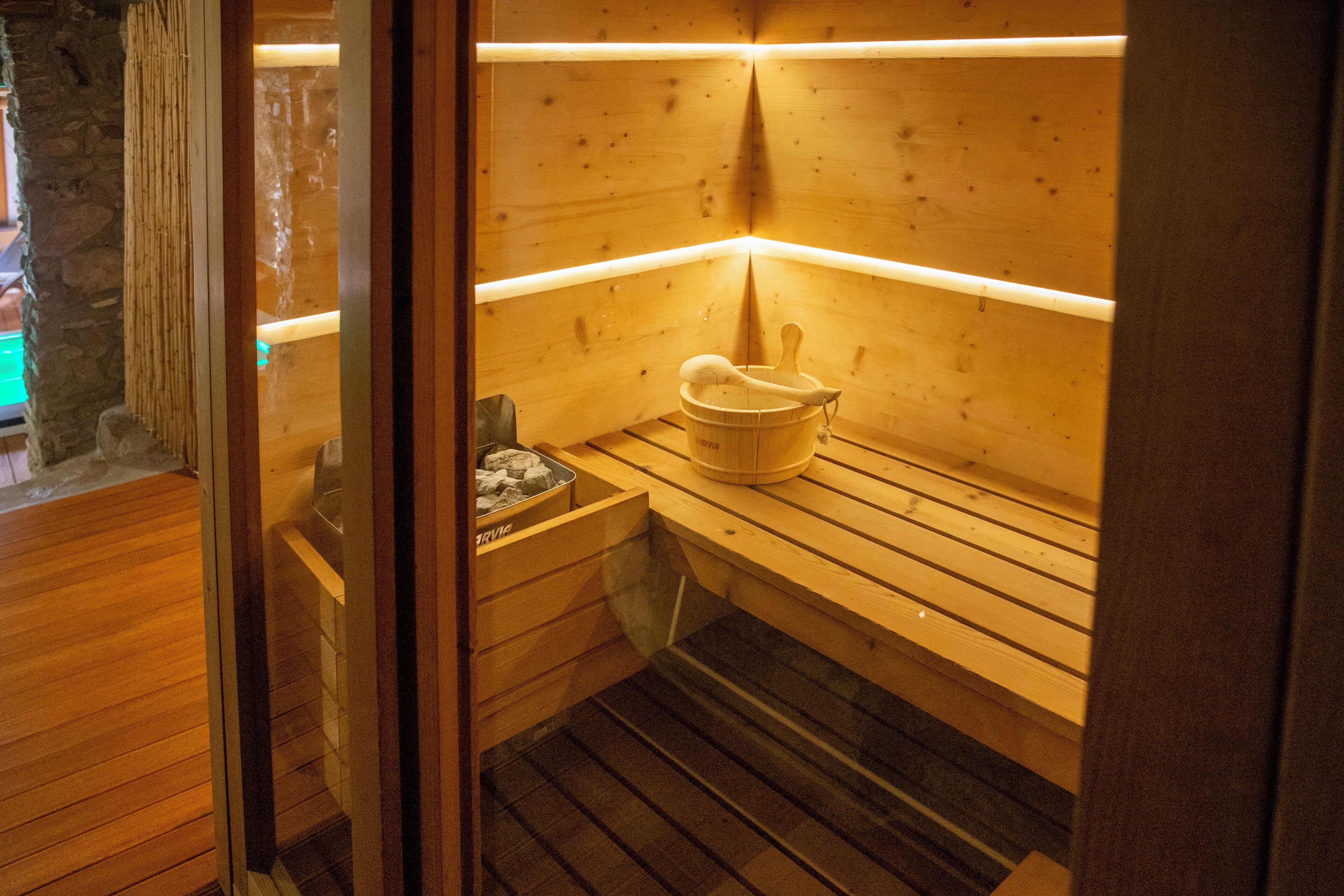 Un sauna avec des bancs en bois et un seau en bois.