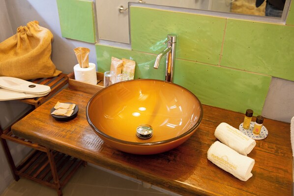 A bathroom with a wooden vanity, a large oval sink, and a green tiled wall. - PORTA SOPRANA Luxury guest house &Spa (Sclafani Bagni)