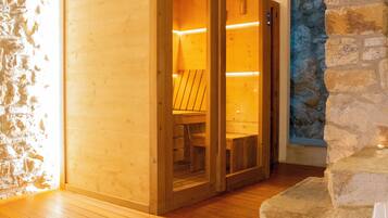 Una sauna de madera con pared de piedra y techo de madera.