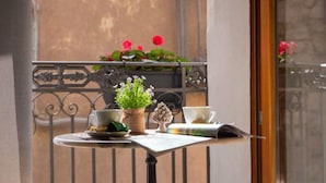 A balcony with a small table, two wicker chairs, a potted plant, a cup, and a newspaper. - PORTA SOPRANA Luxury guest house &Spa (Sclafani Bagni)