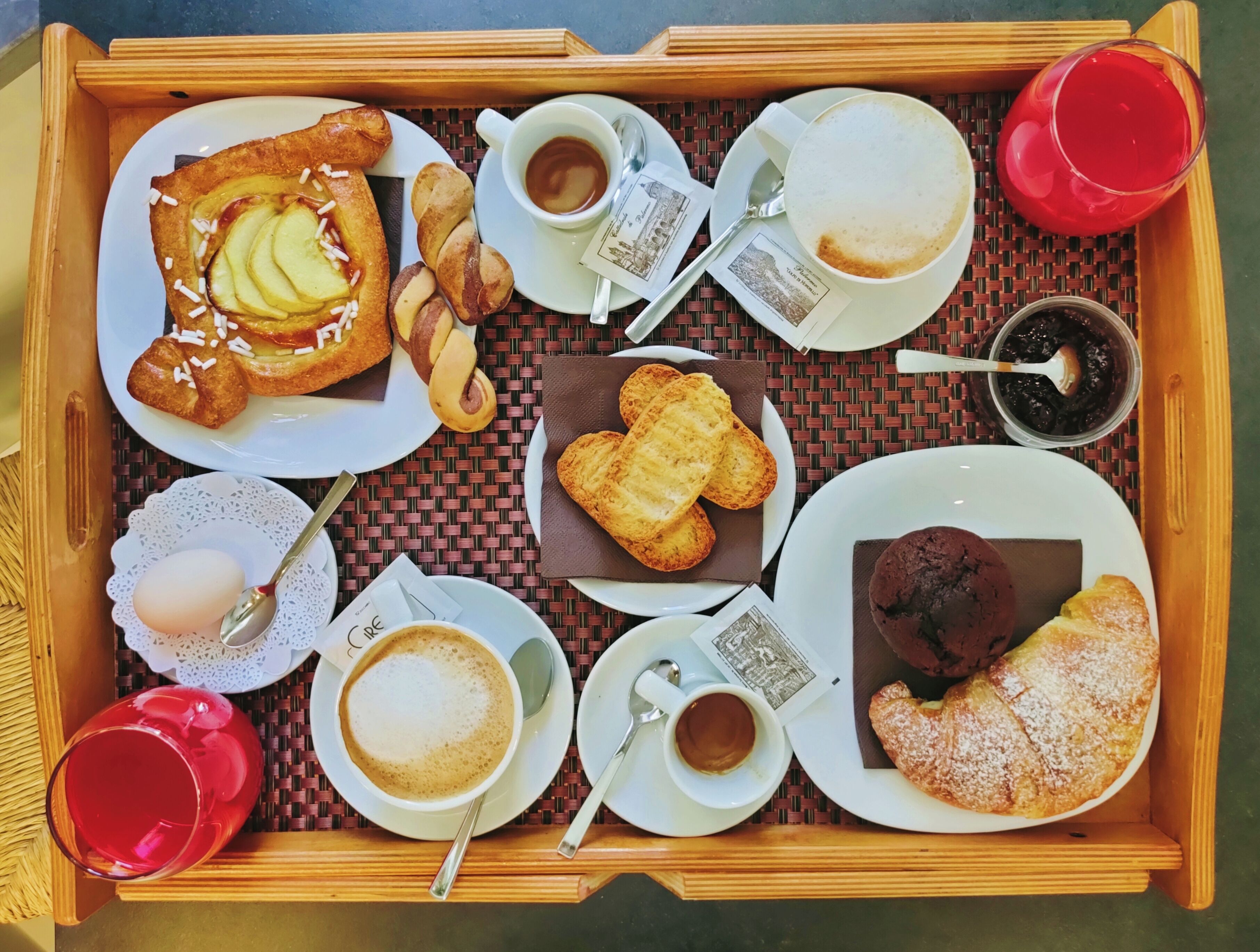 A tray with various breakfast items including pastries, bread, and cups of coffee.