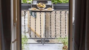A balcony with a table set for a meal, featuring a bowl of fruit and pastries, and a cup of coffee. - PORTA SOPRANA Luxury guest house &Spa (Sclafani Bagni)