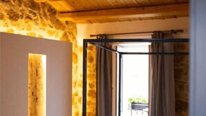 A bedroom with a stone wall, a wooden ceiling, a bed with towels, and a chair. - PORTA SOPRANA Luxury guest house &Spa (Sclafani Bagni)