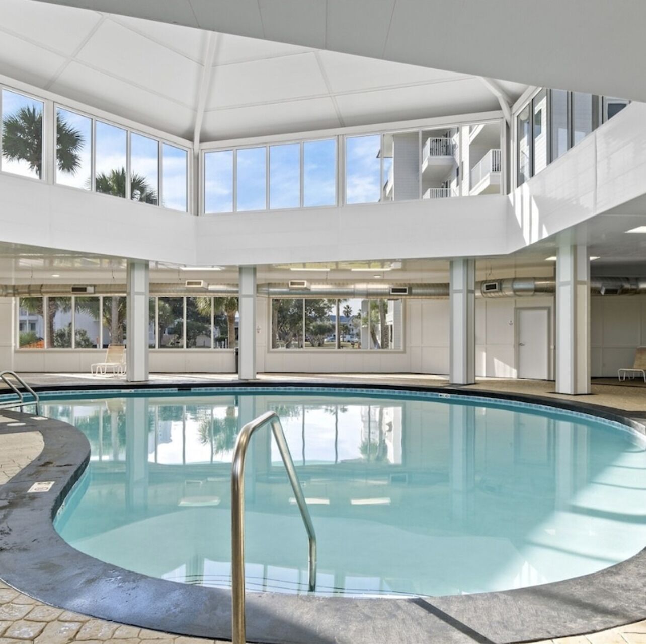 Ein Hallenbad mit freiem Blick auf die umliegende Architektur, darunter ein Balkon und große Fenster.