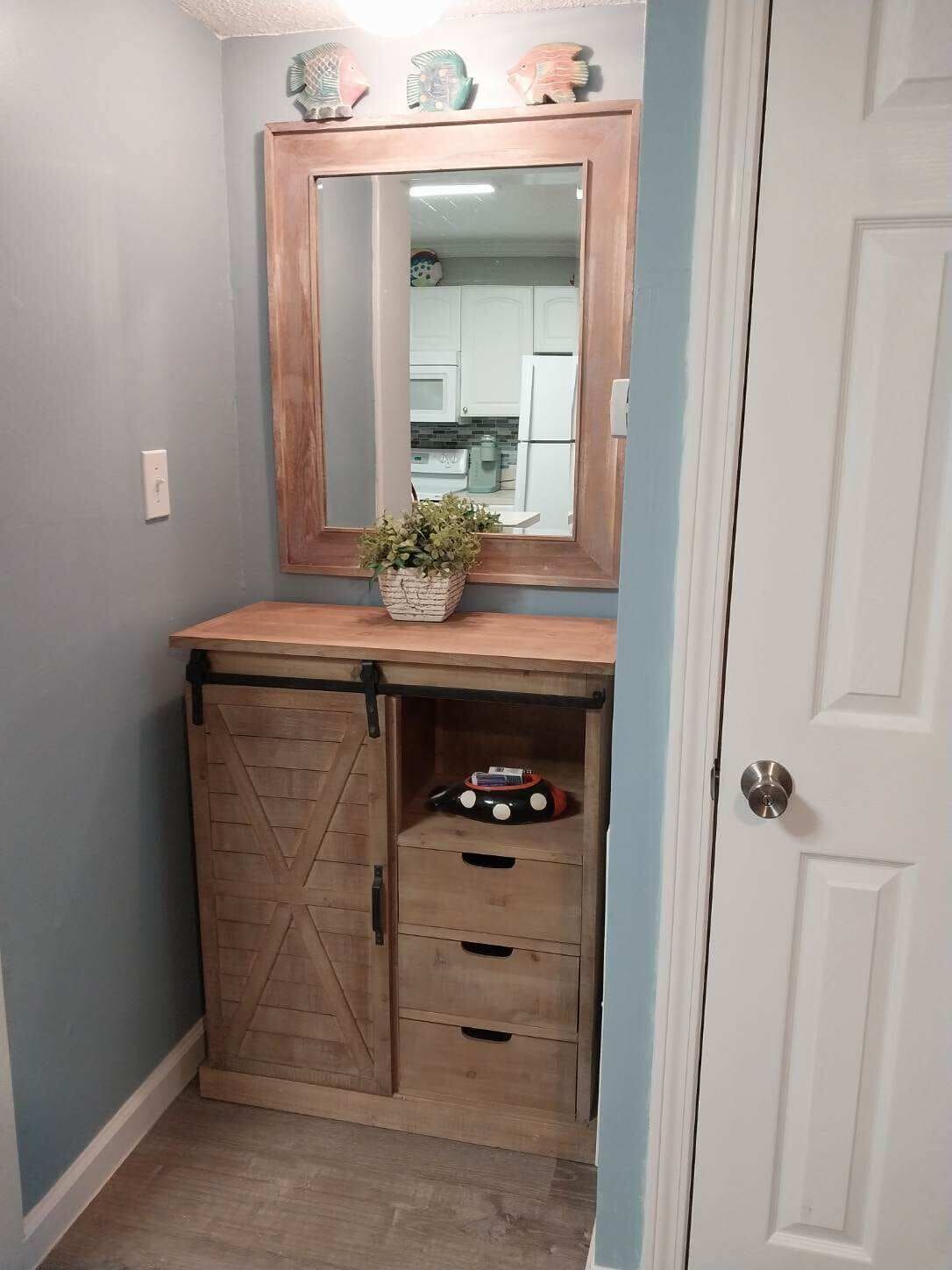 A small bathroom with a wooden vanity, a mirror, a plant, and a toy car.