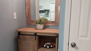 Ein kleines Badezimmer mit einem Holzboden, einem Spiegel, einer Pflanze und einem Spielzeugauto.