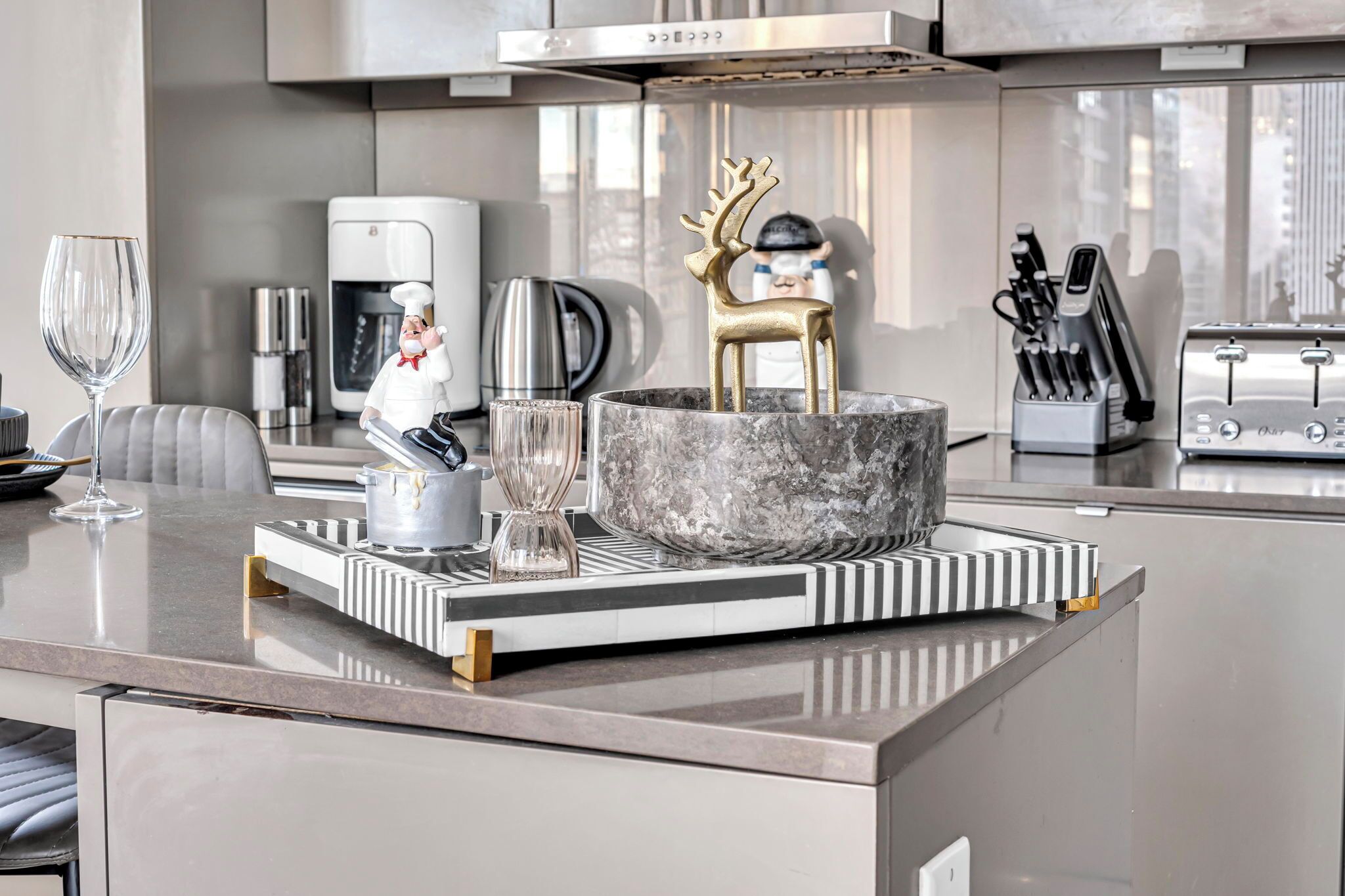 A modern kitchen with a marble countertop, a coffee machine, a toaster, and a decorative deer figurine.