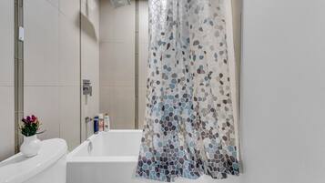 A modern bathroom with a white bathtub, a shower with a rain showerhead, and a mosaic-patterned shower curtain.