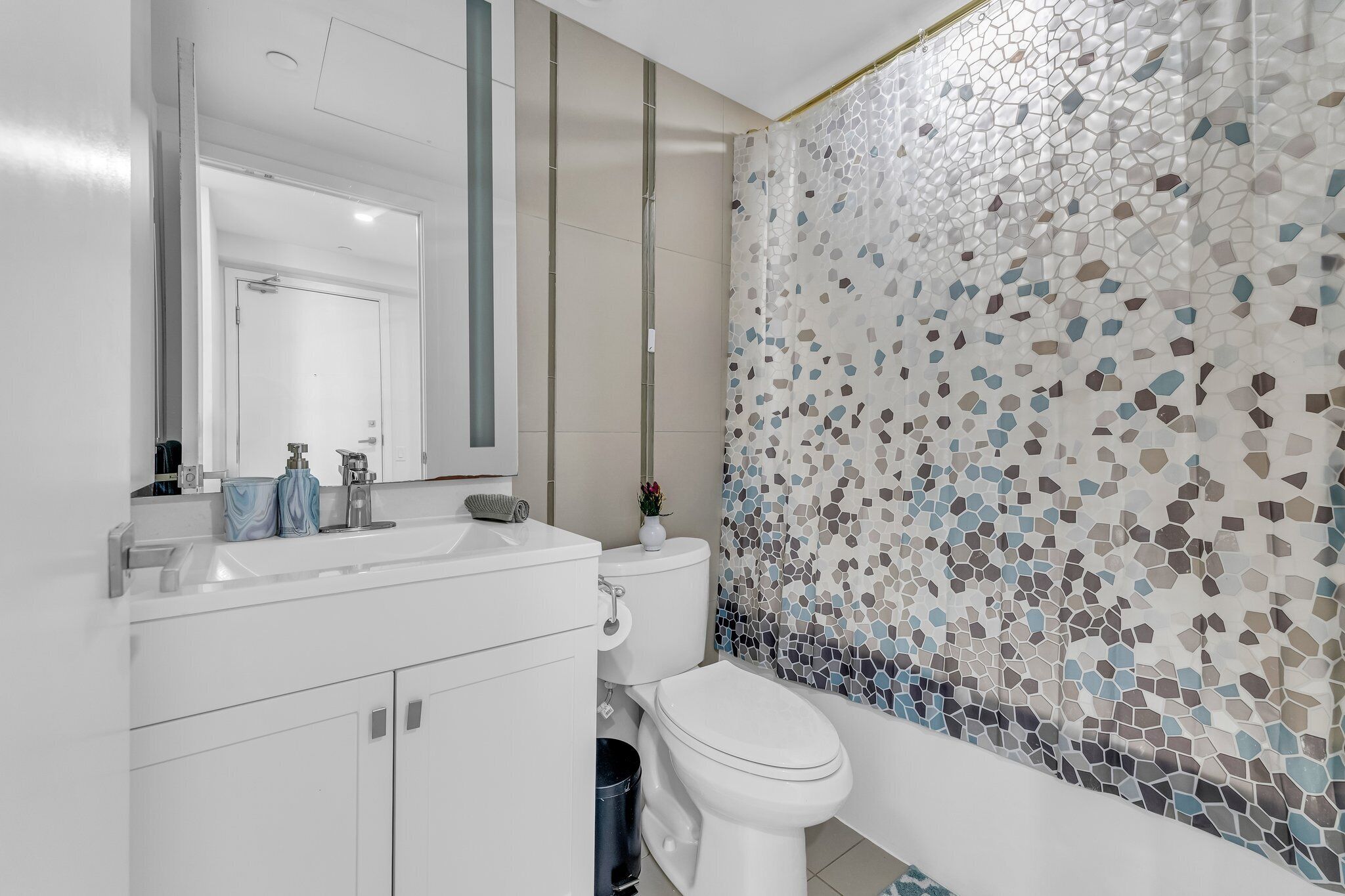 A modern bathroom with a white sink, mirror, and toilet.