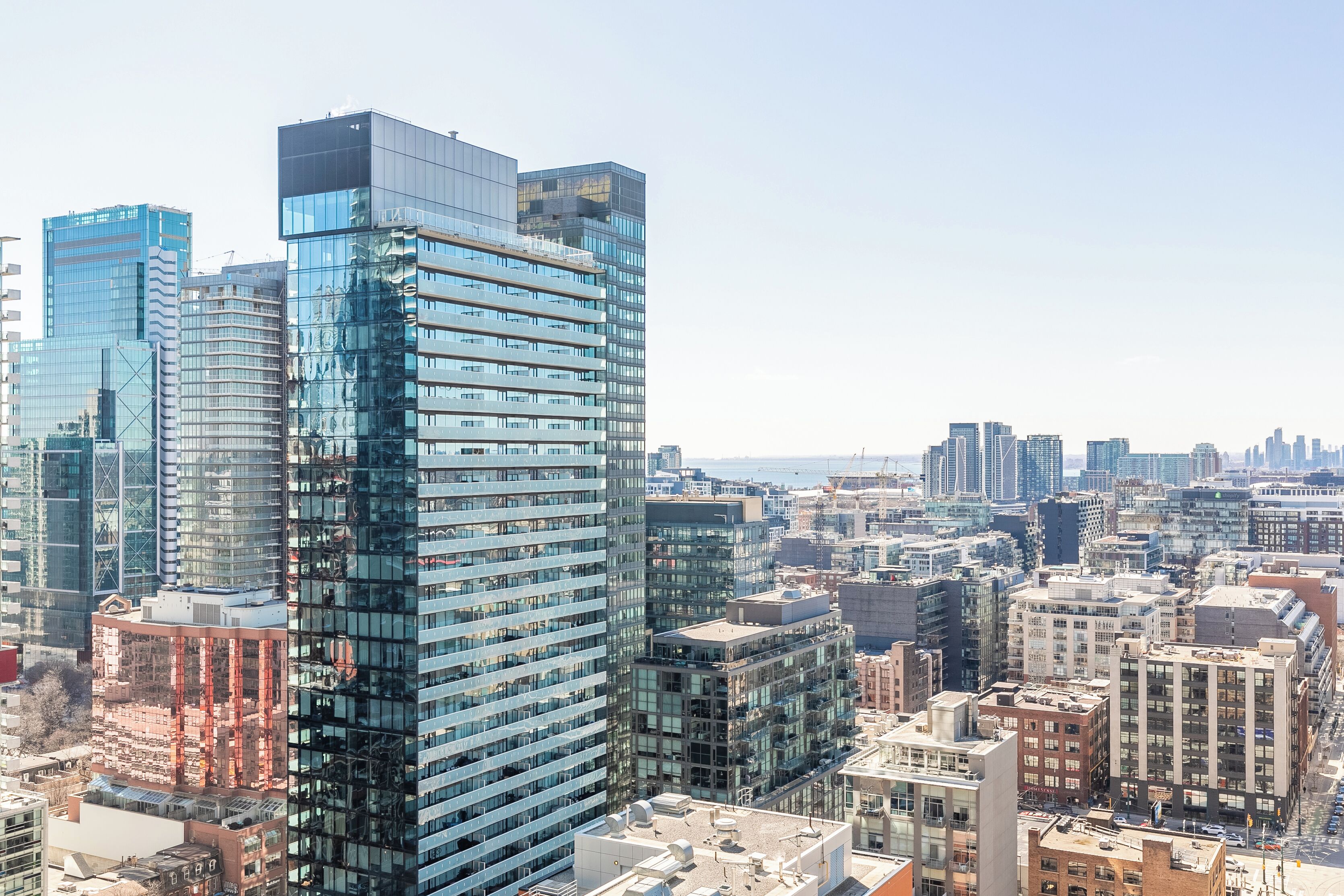 A high-rise building with a modern glass facade, surrounded by other high-rise buildings in a cityscape.
