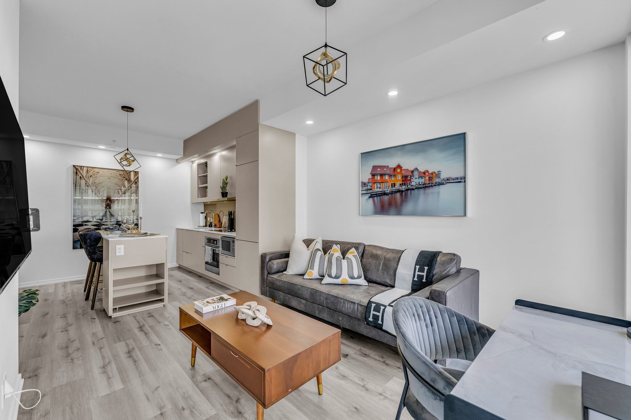 Una sala de estar moderna con un sofá, una mesa de centro y un cuadro de casas en la pared.