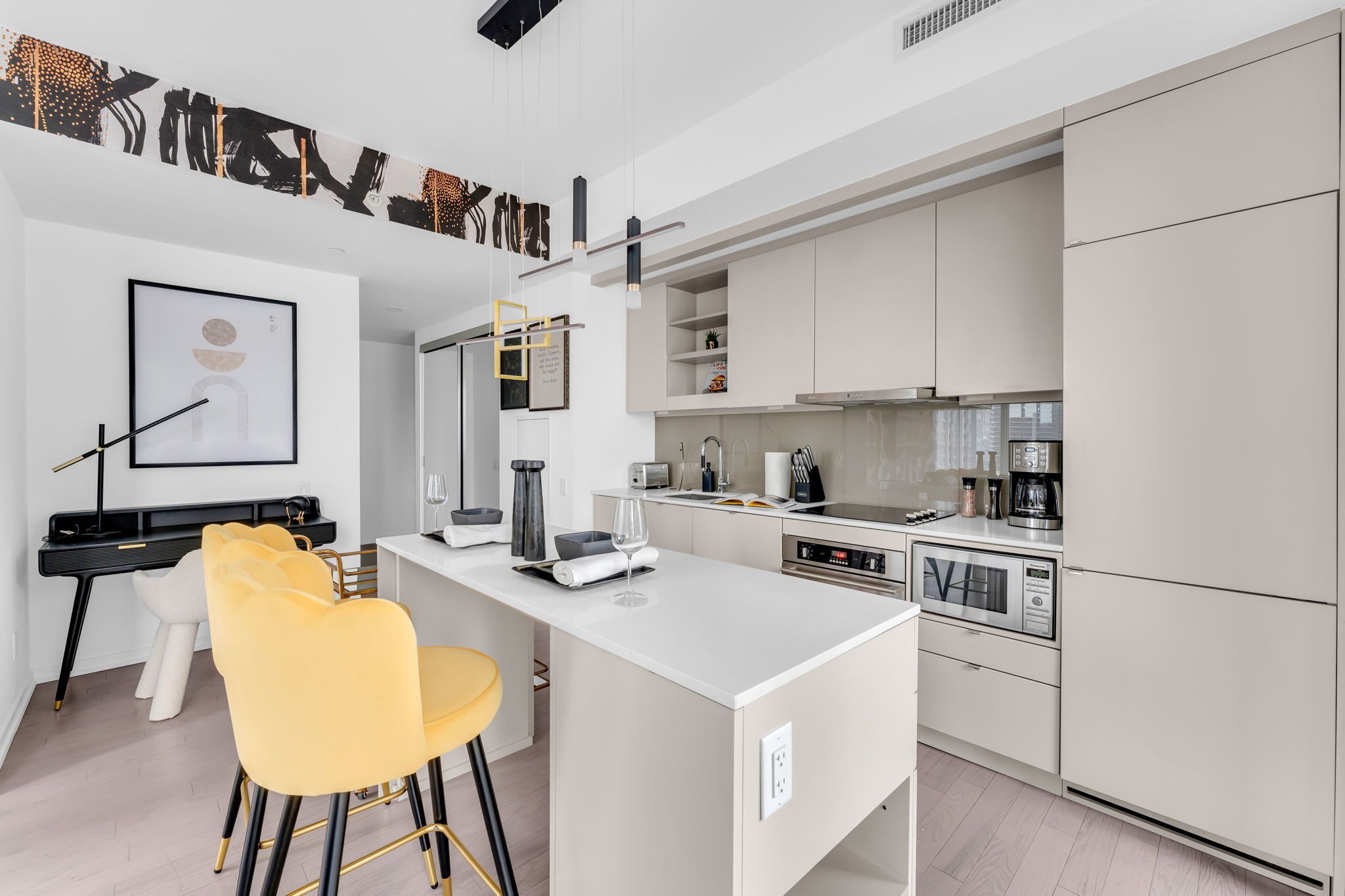 A modern kitchen with white cabinets, a central island, and a dining area with yellow chairs.