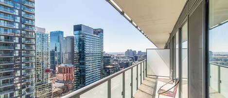 A balcony with a glass railing overlooking a cityscape with modern buildings.