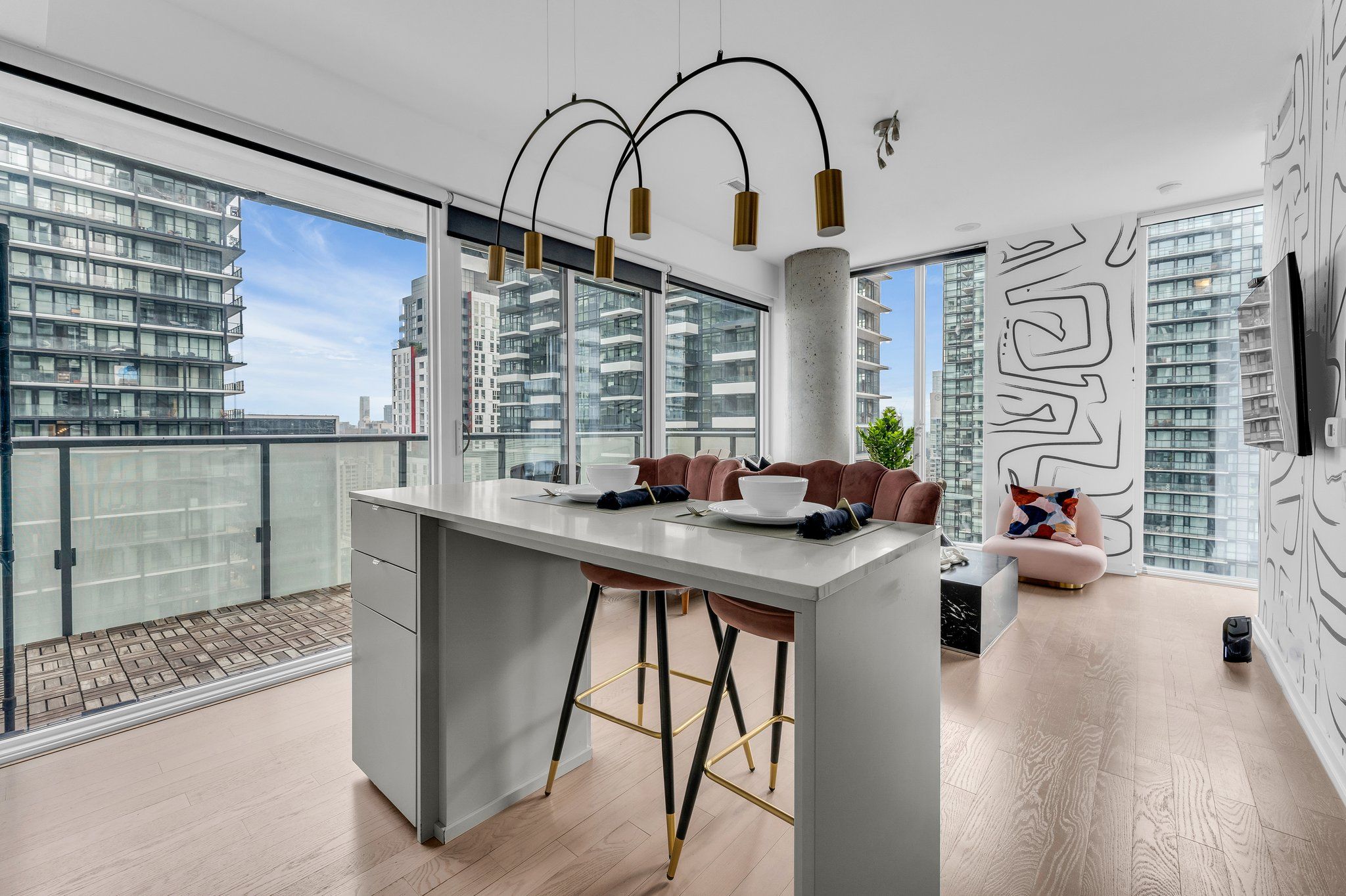 A modern kitchen with a central island, bar stools, and a dining area with a sofa.