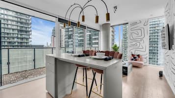 A modern kitchen with a central island, bar stools, and a dining area with a sofa.