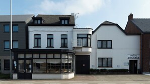 A building with a black-framed glass storefront, a white facade, and a sign reading "INGANG ZWEMBAD".