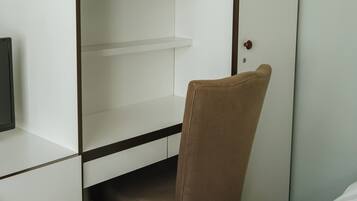 A hotel room with a bed, a desk with a chair, and a wardrobe.