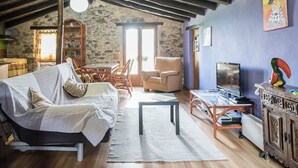 Una habitación rústica con techo de madera, una cama, un televisor y un comedor con sillas y una mesa.
