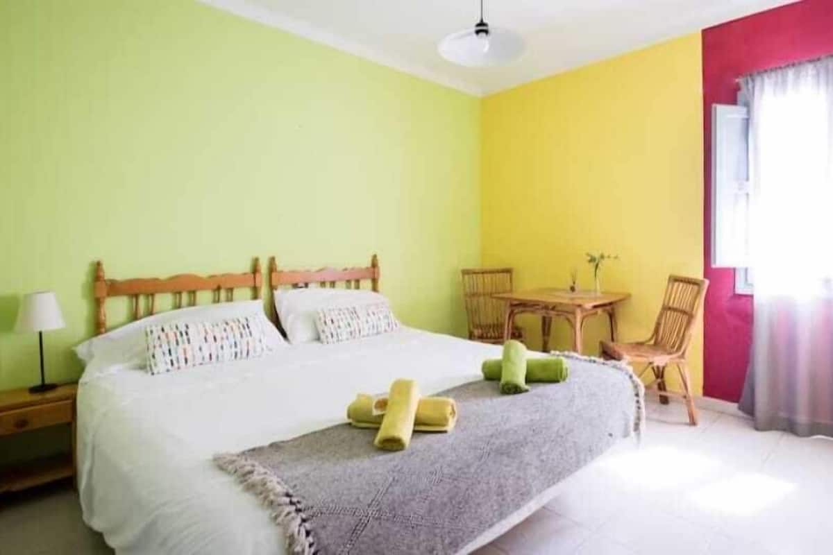 A bedroom with a bed, bedside table, and a small table with chairs.