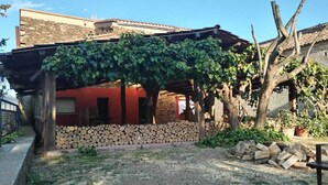 Un edificio rústico con fachada roja, pared de piedra y un espacio cubierto con techo de madera.