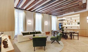 A modern living room with a white sofa, green armchairs, and a dining area with a wooden table and chairs. - LUX - PARISIAN RETREAT:EXQUISITE 3-BEDROOM IN SAINT GERMAIN (Paris)