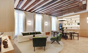 Una sala de estar moderna con sofá, sillas, una mesa de comedor y una zona de cocina con armarios y encimera.
