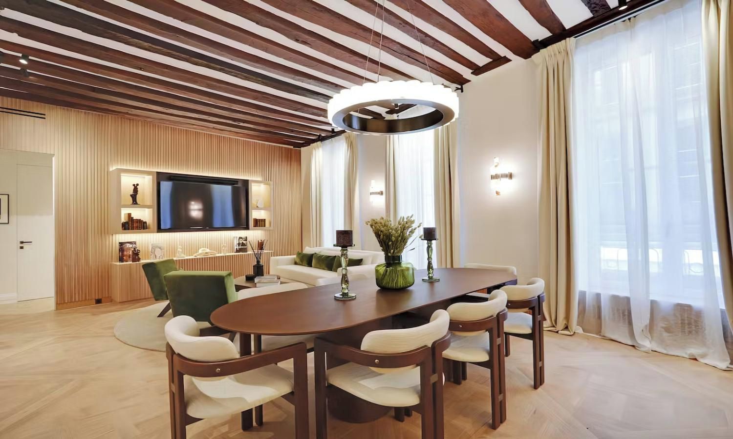 Un salon moderne avec un plafond en bois, un grand téléviseur à écran plat, une table à manger avec des chaises et un canapé.