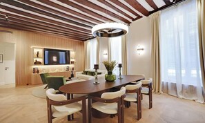 En moderne stue med træloft, stort fladskærms-tv, spisebord med stole og sofa.