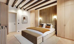 A bedroom with a large bed, wooden wardrobe, and a built-in bench. - LUX - PARISIAN RETREAT:EXQUISITE 3-BEDROOM IN SAINT GERMAIN (Paris)