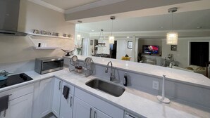 A modern kitchen with white cabinetry, a stainless steel sink, and a built-in microwave. - Minutes from I495/200/95, DC and VA. Family sized guest suite with games to play (Silver Spring)