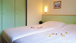 Una habitación de hotel con una cama, una mesita de noche, una lámpara de pared y un cuadro en la pared.