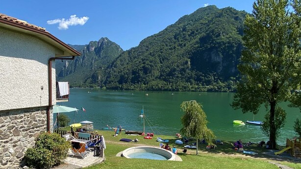 Una propiedad frente al lago con piscina, mobiliario exterior y vistas al lago y las montañas.