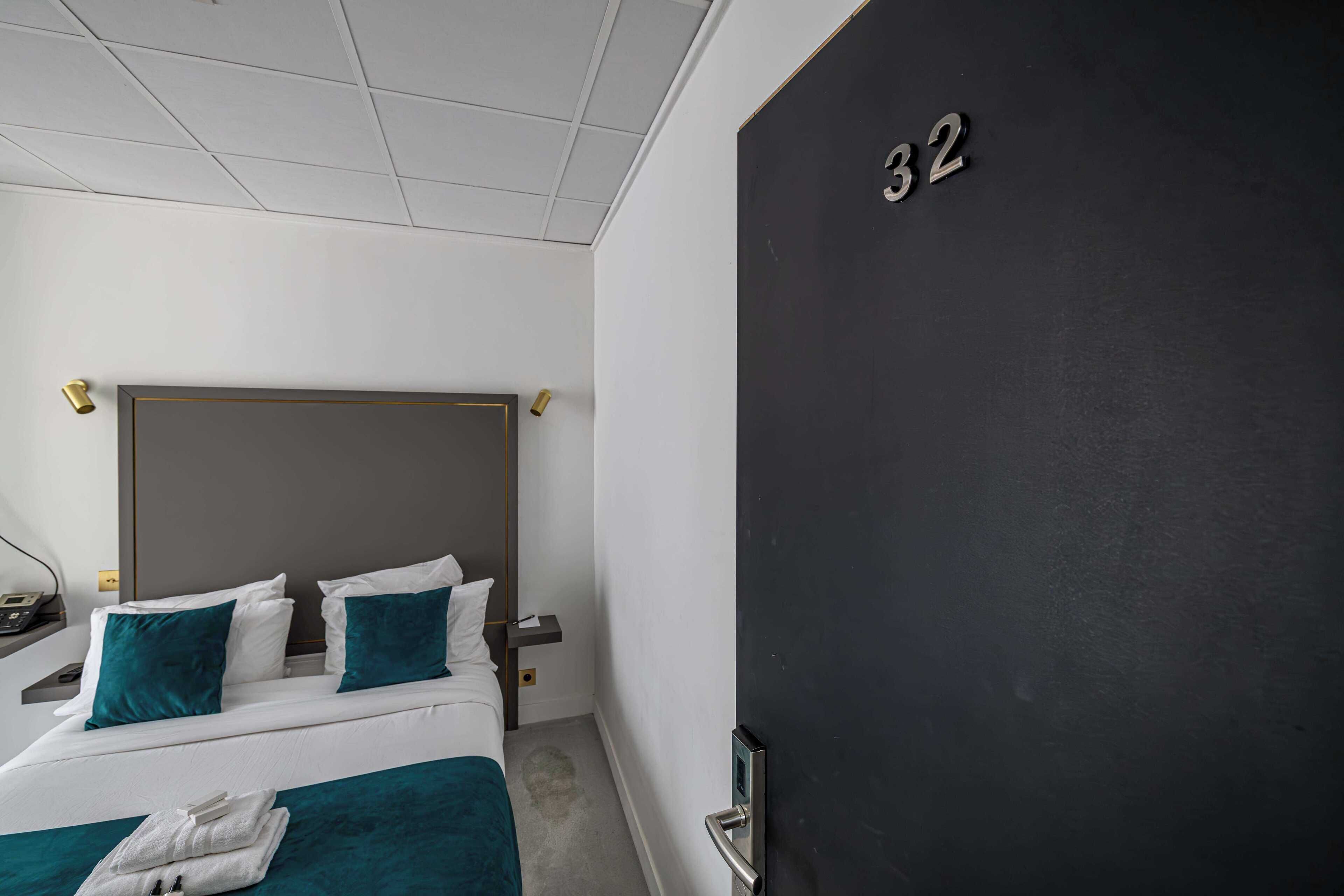 Una habitación de hotel con una cama, una mesita de noche y una puerta con el número 32.