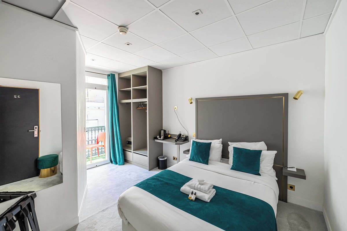 Una camera d'albergo moderna con un letto grande, una scrivania e vista sul balcone esterno.