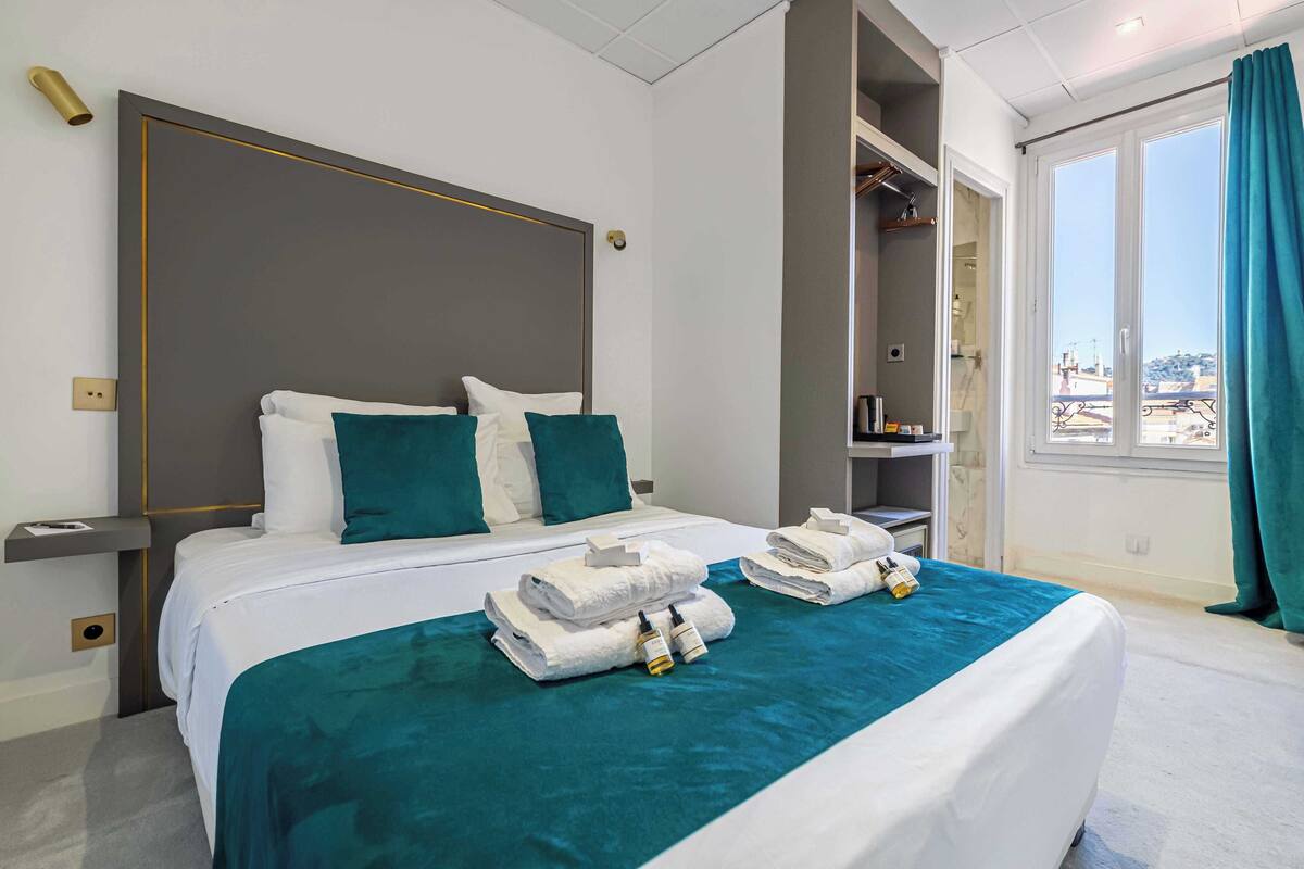 Camera d'albergo con un letto grande, un armadio, un bagno e vista sulla città.