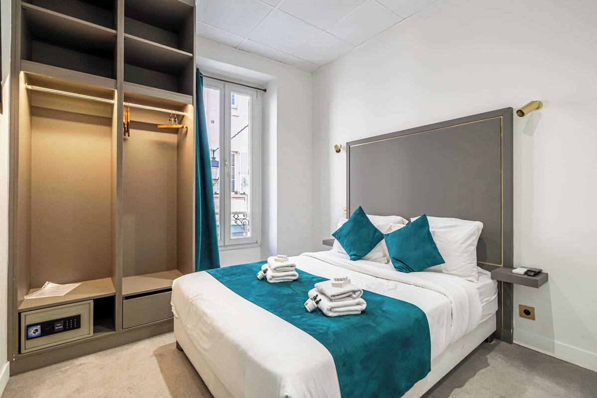 Una camera d'albergo con un letto, un armadio a muro e vista dalla finestra.