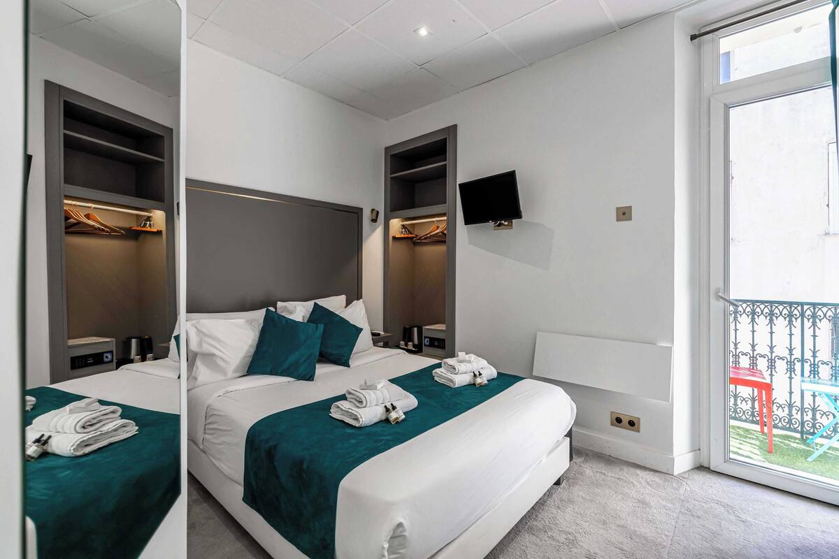Una camera d'albergo con due letti, una televisione, un balcone e un armadio.