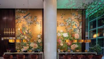 A reception area with a large column, floral wall art, and a seating area with chairs.